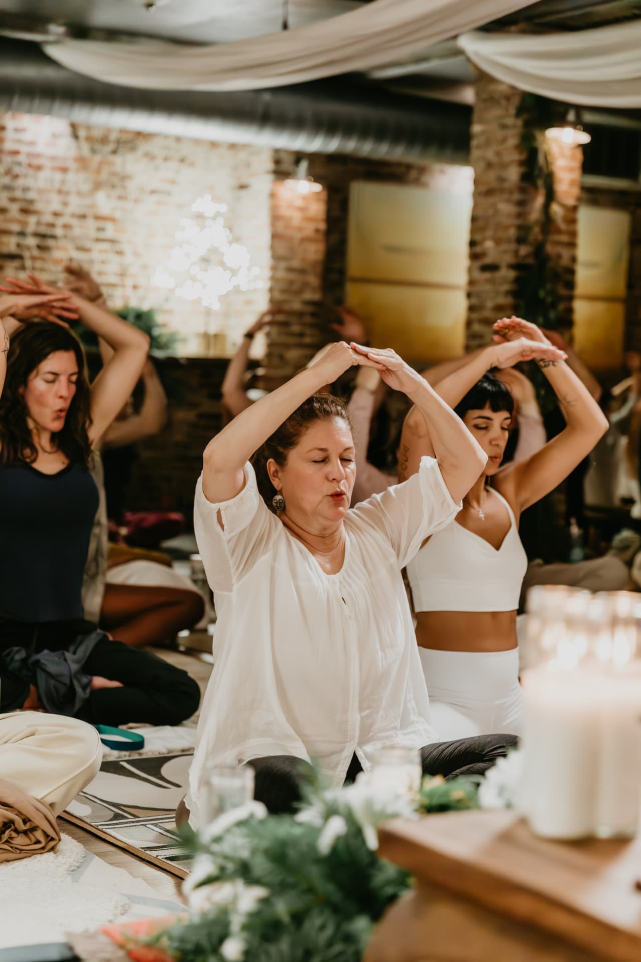 Participants with arms raised in practice beside candles