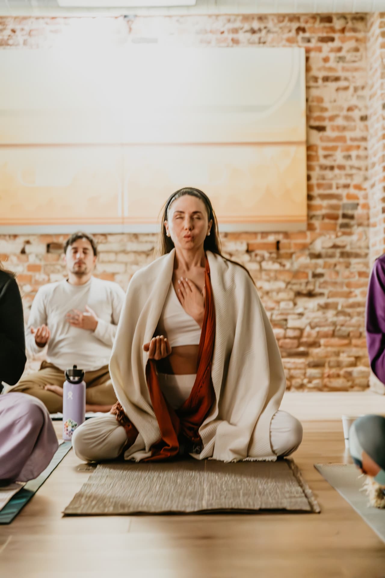 Participant wrapped in a cream shawl seated in meditation