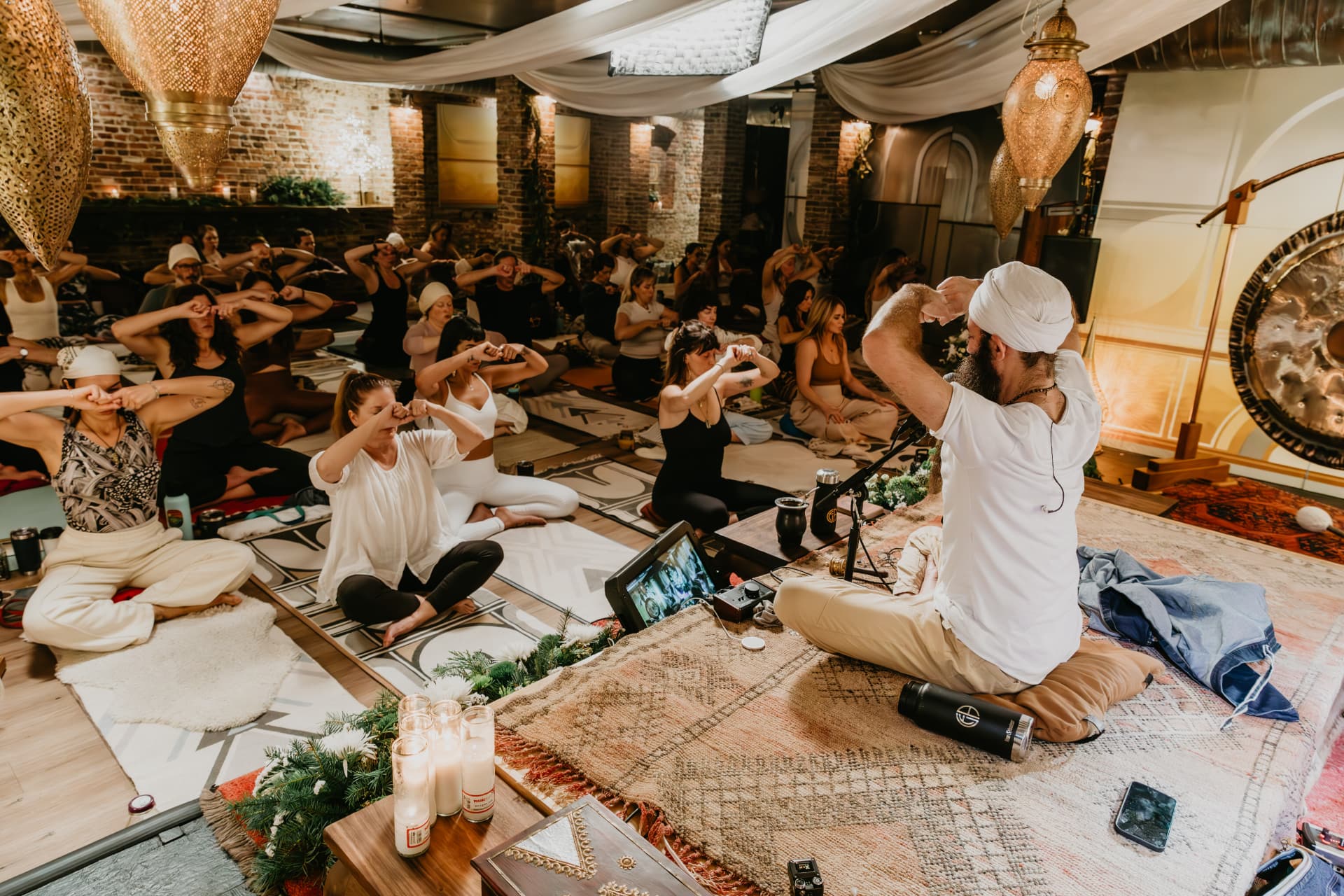 Teacher leading a candlelit kundalini practice in the brick studio