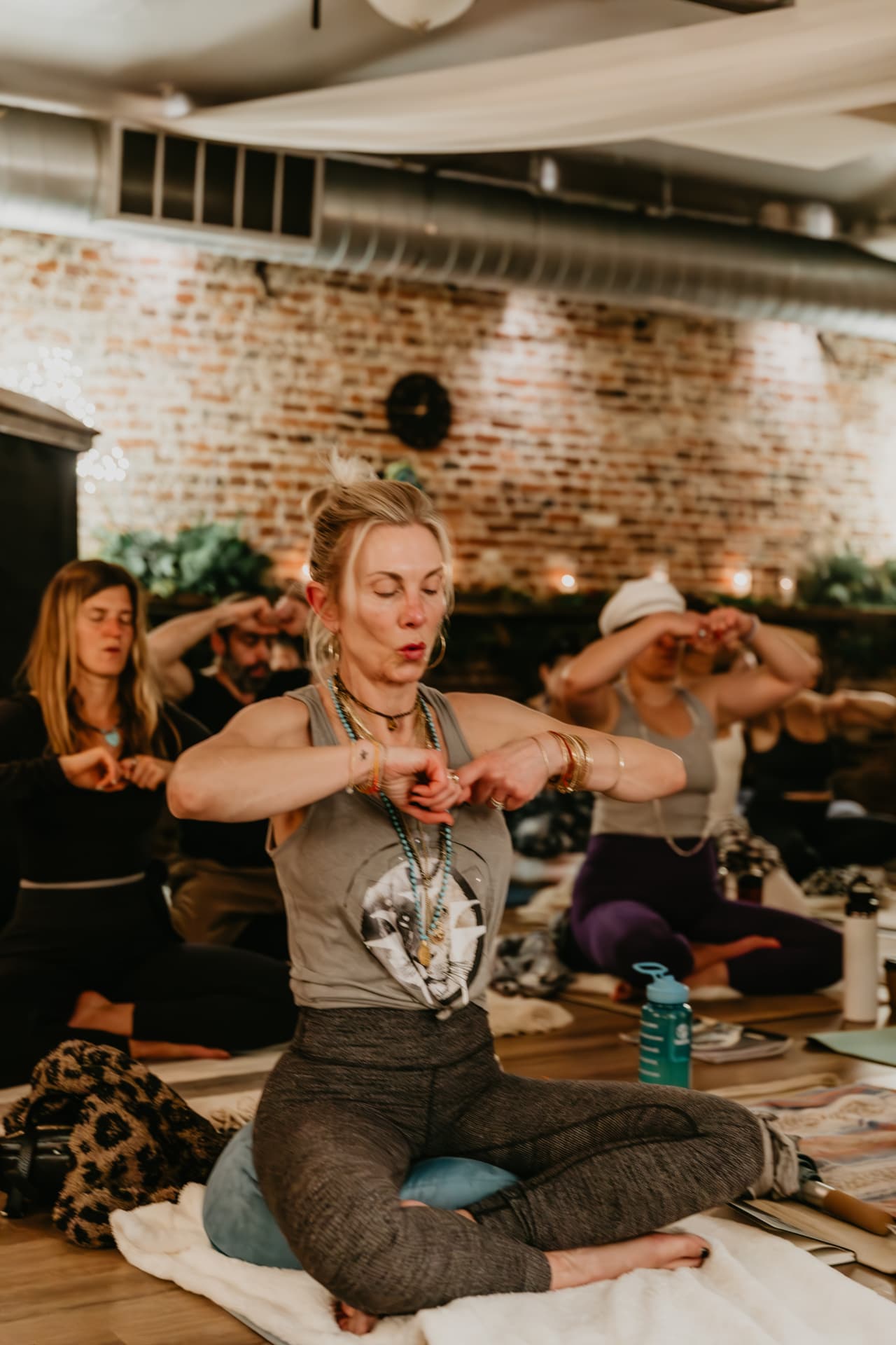 Participant seated in breathwork practice against exposed brick